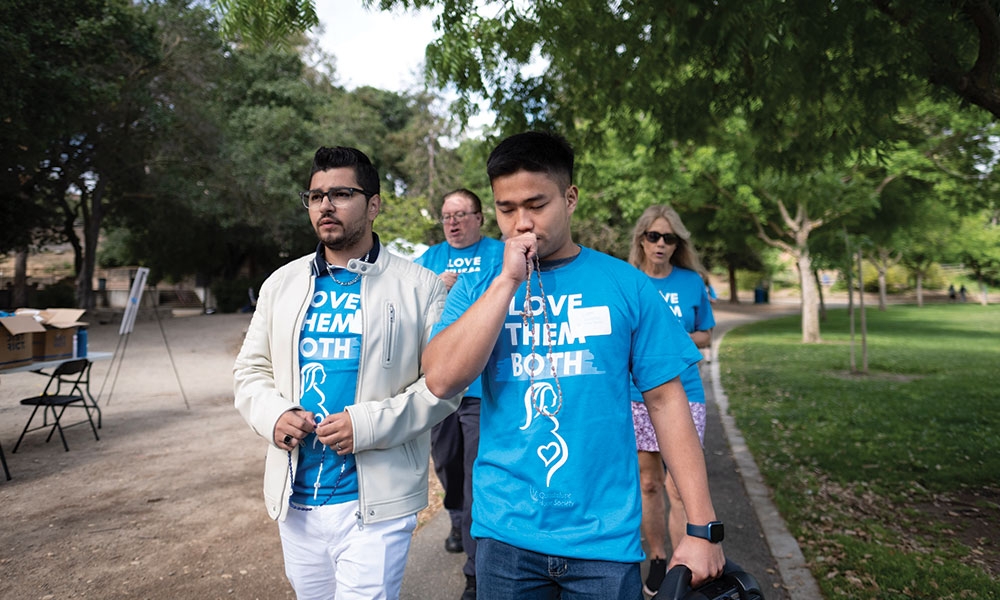 Two Young Adults wearing teal Tshirts reciting rosary during organized walk
