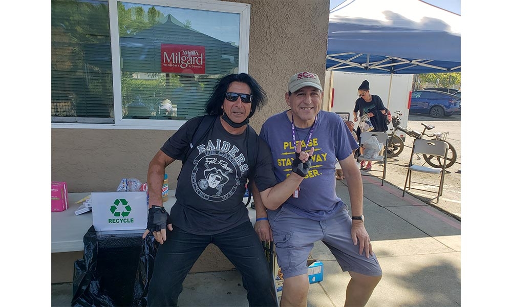 Two men sit outdoors in shade