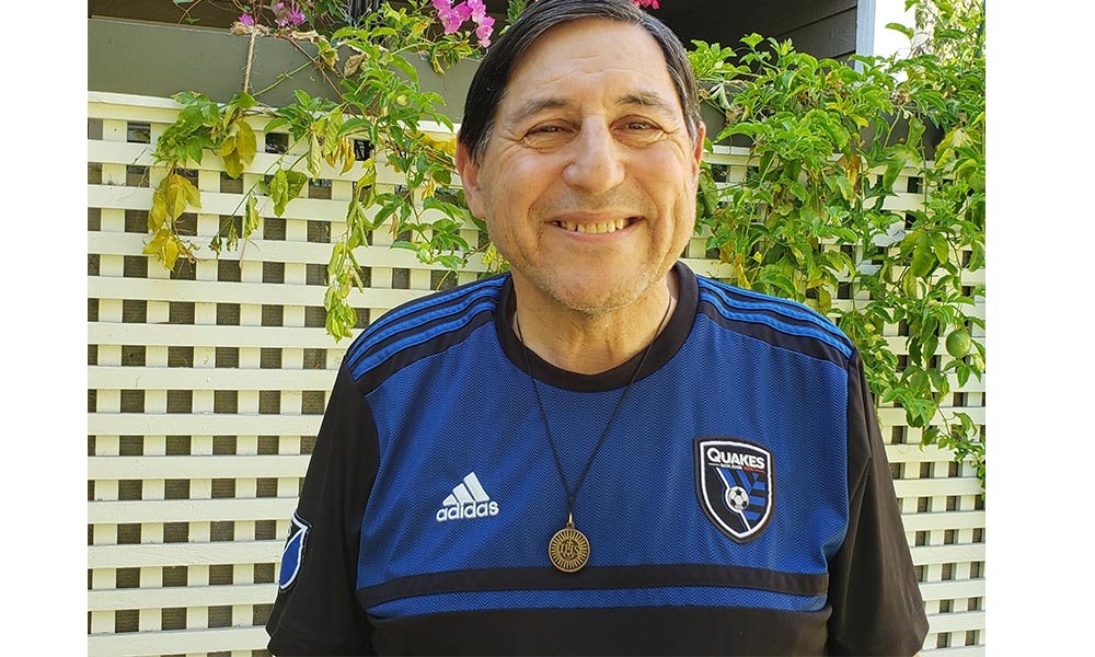 Portrait of man wearing royal blue jersey in front of trellis