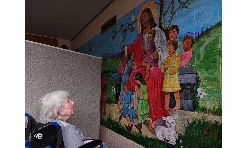 Joann in wheelchair looking at mural of Jesus