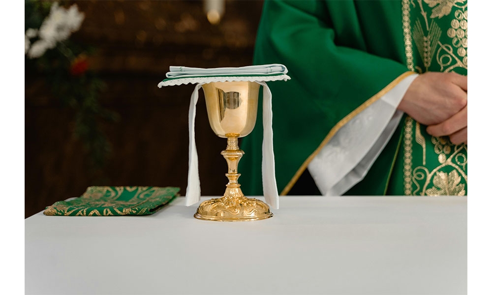 Chalice on altar, priest in green vestments