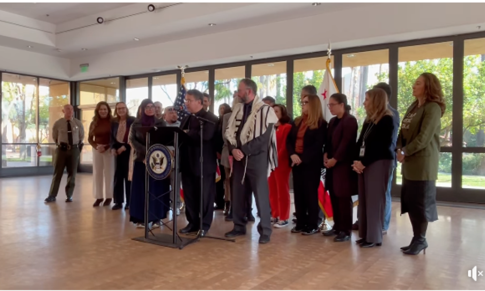 Bishop Cantú stands at podium alongside a group of community and faith leaders